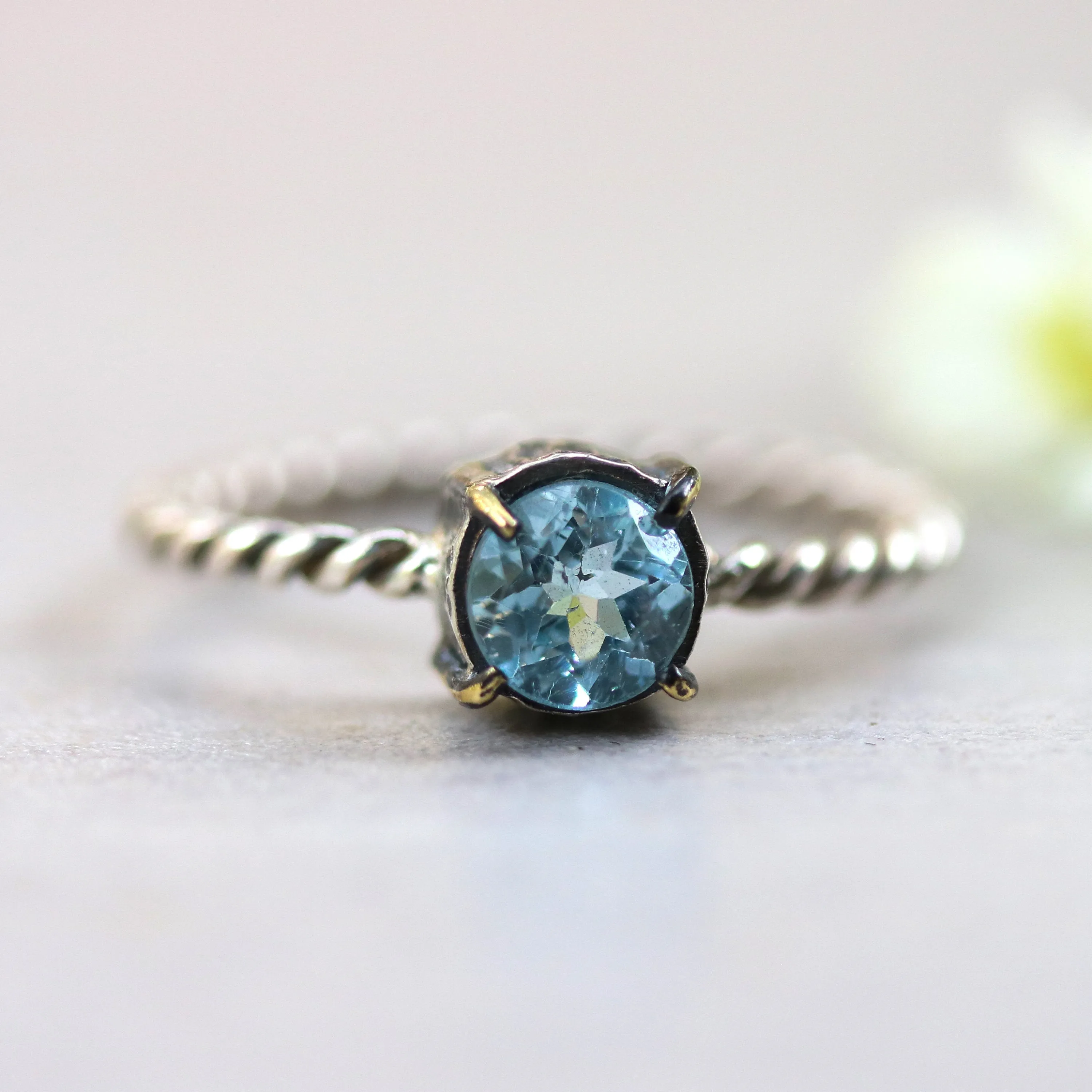 Round faceted blue topaz ring in silver bezel and brass prongs setting with sterling silver twist design band